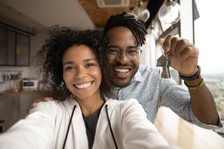 Head shot portrait overjoyed African American married couple showing keys, happy wife and husband, homeowners or tenants making selfie, purchased first dwelling, new apartment, mortgage concept